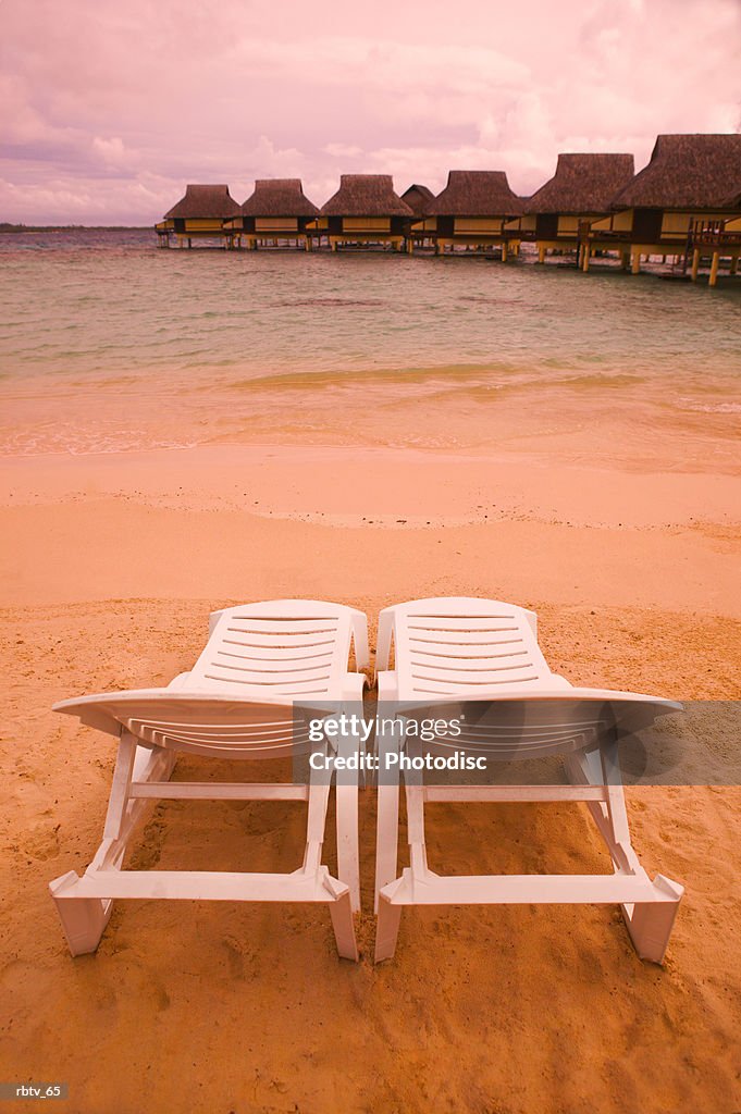 Landscape photograph of two empty beach chairs overlooking a beautiful beach and resort