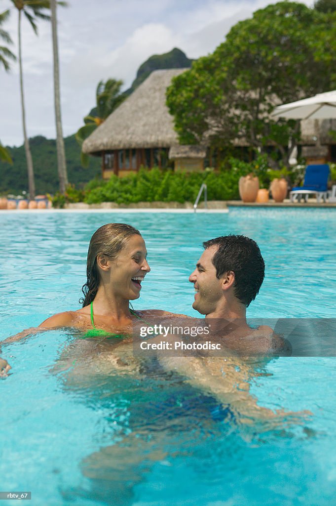 A caucasian couple swim and play in a pool at a tropical resort