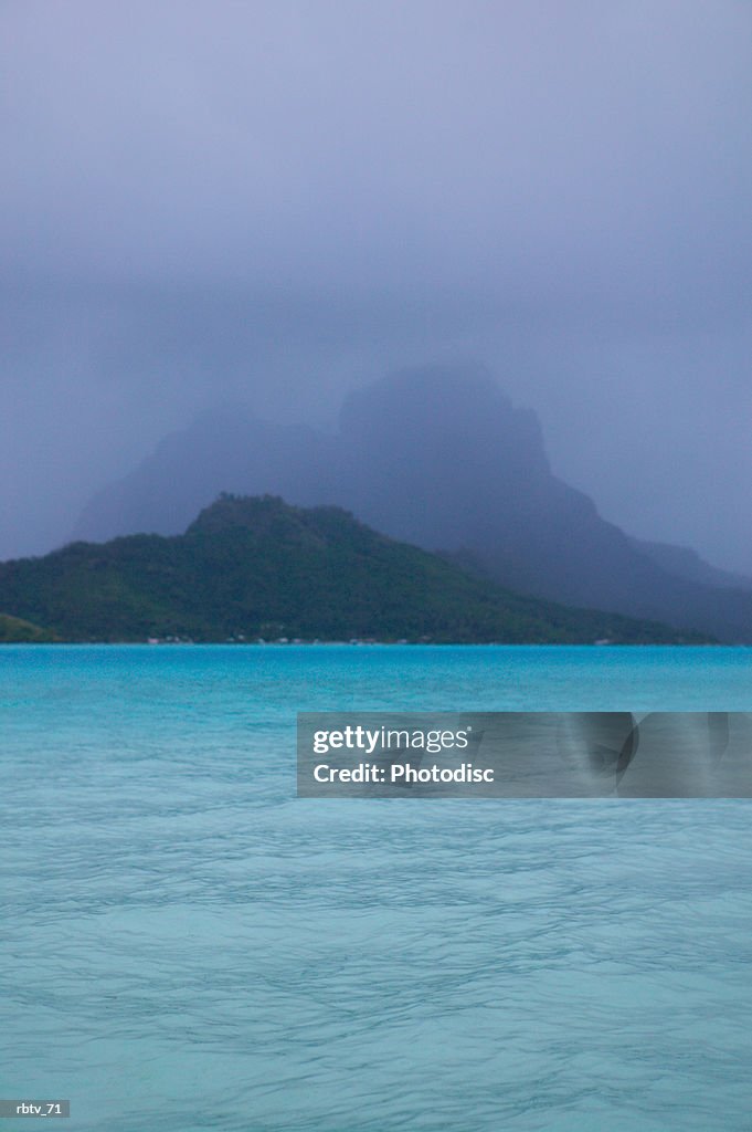 Landscape photograph of crystal clear water and tropical mountains through the mist