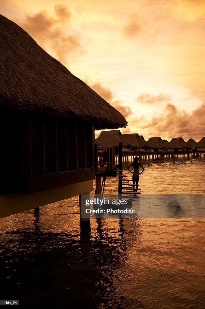 Landscape photograph of a grass hut over the water at sunset