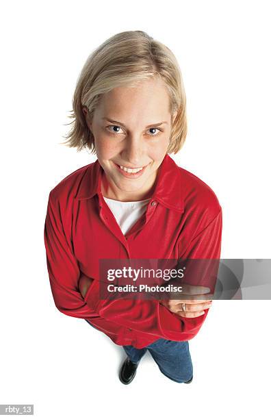 cute pretty young woman with short blonde hair wearing a long sleeved red shirt blue jeans and a white tee-shirt folds her arms as she smiles up at the camera - tee shirt stockfoto's en -beelden