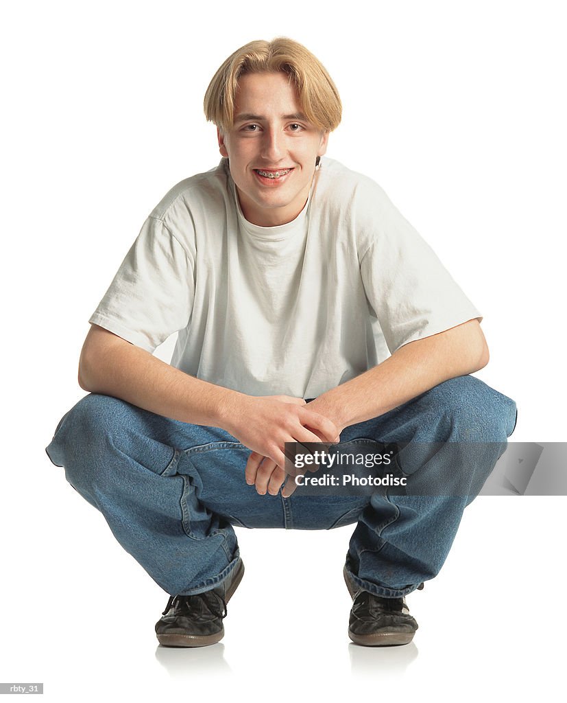 Teenage Boy With Longer Blonde Hair And Braces Wearing A White Tshirt Blue  Jeans And Black Soccer Shoes Squats Down And Smiles Into The Camera  High-Res Stock Photo - Getty Images