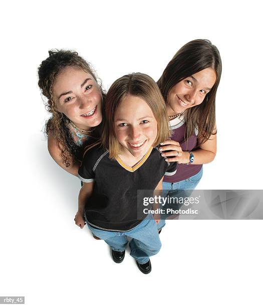 three teenage caucasian girls smile up at the camera playfully - smile stockfoto's en -beelden