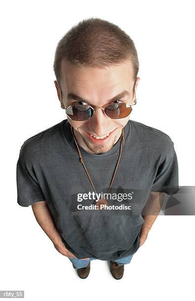 caucasian teenage male wearing a gray tee shirt smiles mischievously into the camera - tee shirt stockfoto's en -beelden