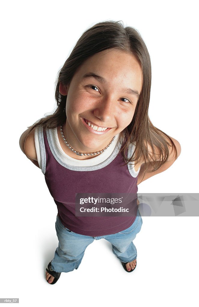 Young teenage caucasian girl wearing a purple tanktop and blue jeans smiles while looking up into the camera