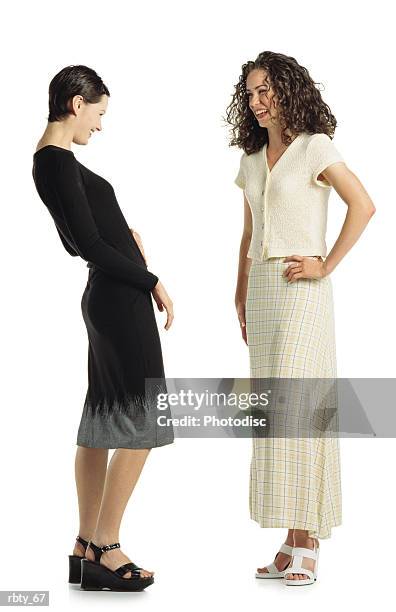 two young caucasian women wearing dresses stand together talking and laughing together - women talking stock pictures, royalty-free photos & images