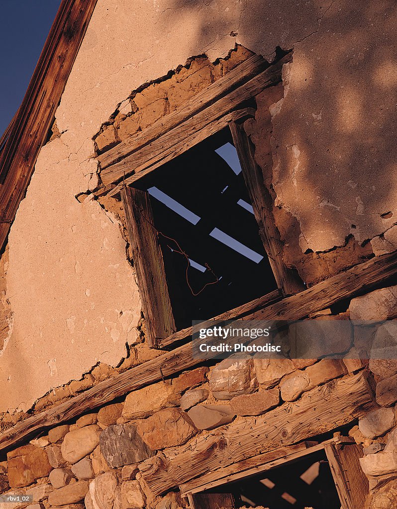 An old wooden and stone building with its window showing a ceiling that_s falling apart