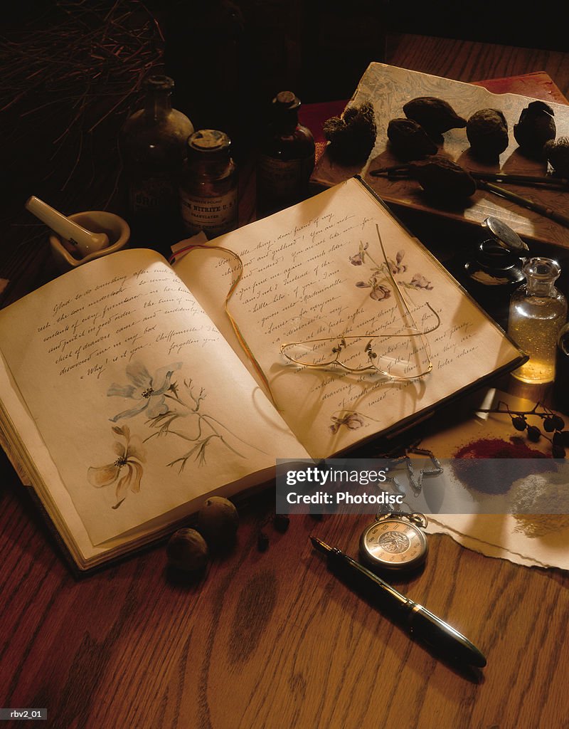 Several small items from a journal with sketches to herbs lay on a wood table