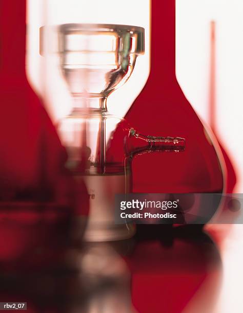 a series of red flasks and beakers stand on a shiny table with a white background - stand up ストックフォトと画像