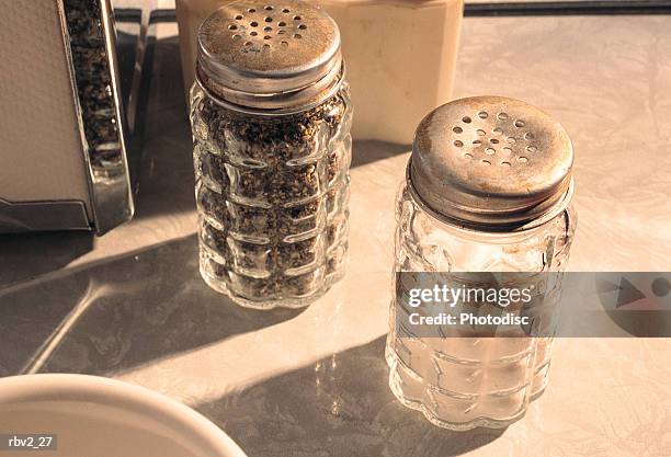 salt and pepper shakers sit on a marble table next to a bowl and napkin holder - napkin holder stock pictures, royalty-free photos & images