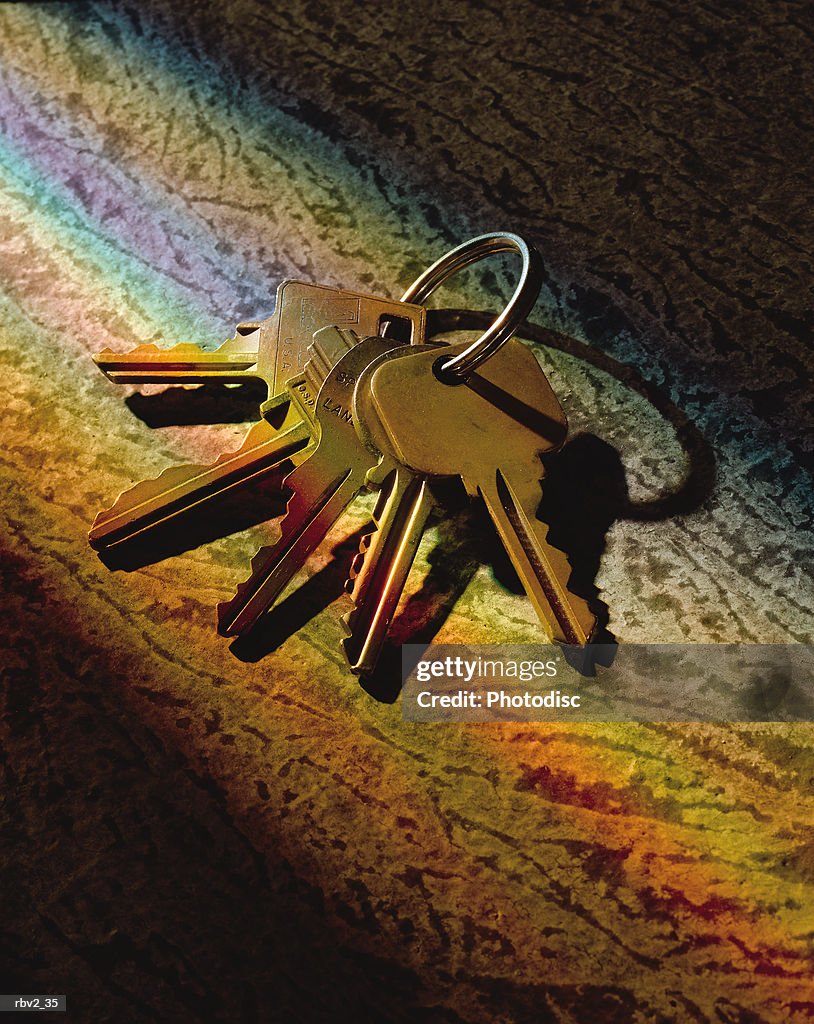 Keys on a key ring lie on an abstract diagonal surface as rainbow colors cross them