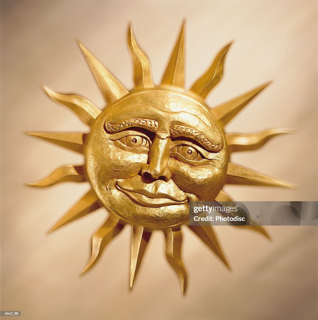 A smiling bronze cast sun rests on a cream background