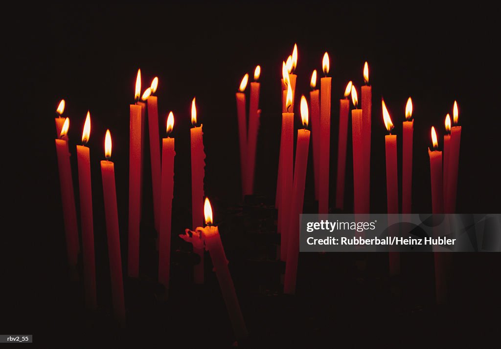 Red wax candles are lit showing their bright flames on a black background