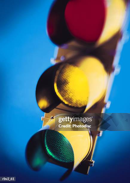 a lit red and yellow and green traffic light on top of a blue background - yellow light stock pictures, royalty-free photos & images