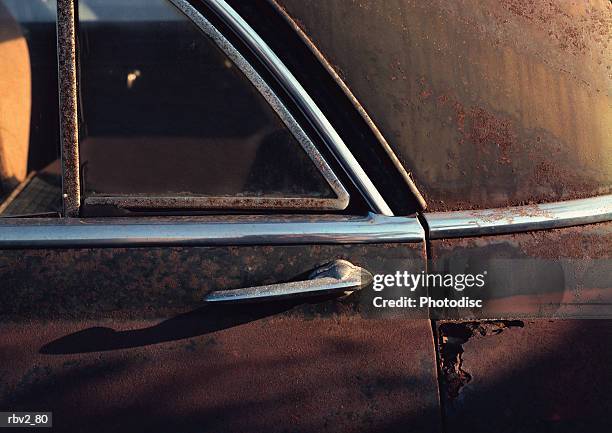 an old rusted car door holds a handle and stickers - door stockfoto's en -beelden