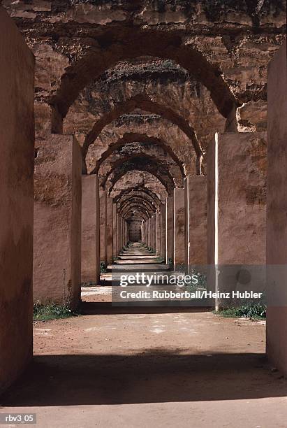 gray stone columns support stone arches as sun light shines between the archways on green plants - redstone stock pictures, royalty-free photos & images