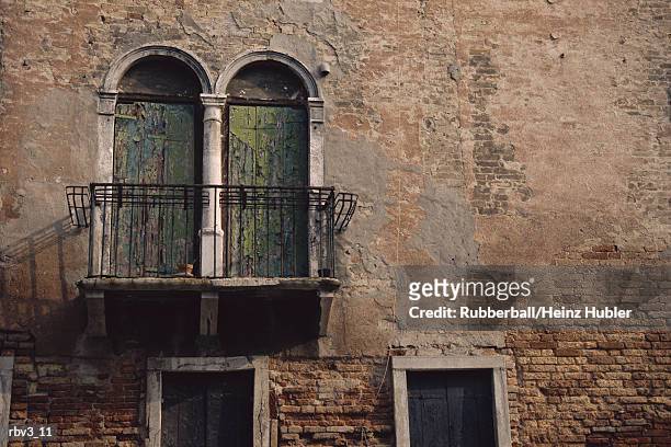 glass windows with balconies stand next to each other on a brown stucco wall - next stockfoto's en -beelden