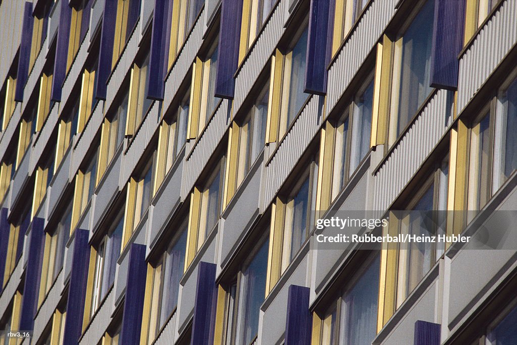 Looking up a business wall covered with windows sided with yellow and white material