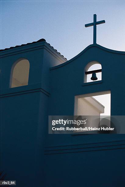 a bell hangs from a white stucco mission home under a blue sky - bell stock-fotos und bilder