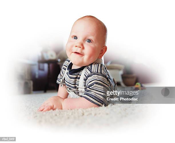 a smiling caucasian baby boy is crawling on a white carpet and smiling at the camera - only baby boys stock pictures, royalty-free photos & images