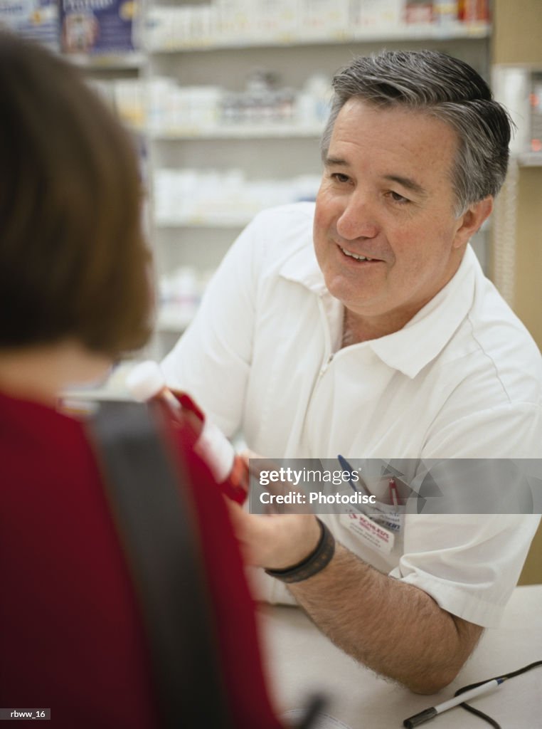 A pharmacist helps a customer with her prescription medication