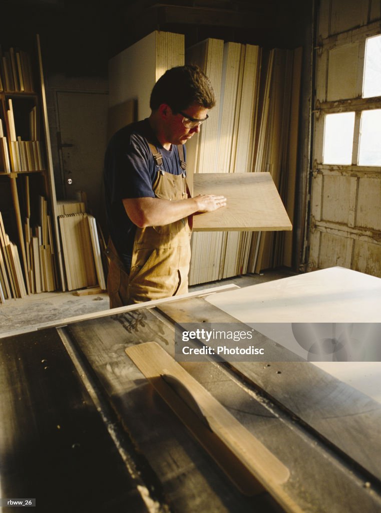 A caucasian  carpender inspects a rectangular board