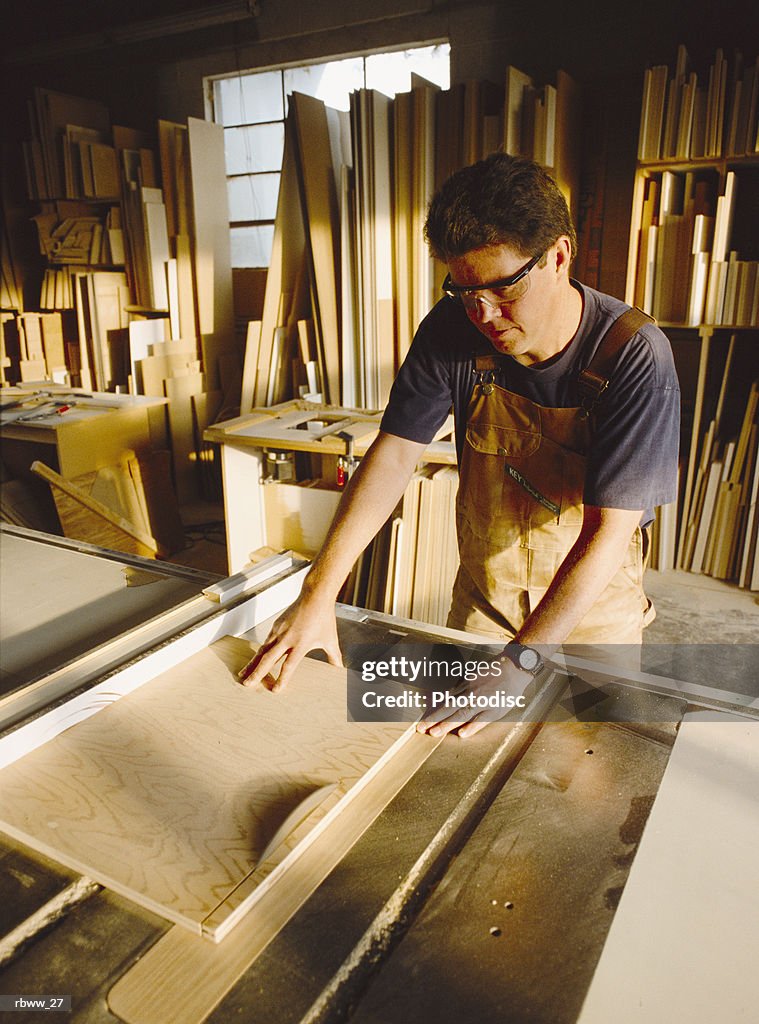 A carpenter cuts a board with a saw