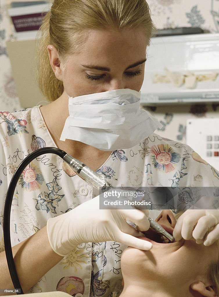 A dental assistant cleans the teeth of a patient