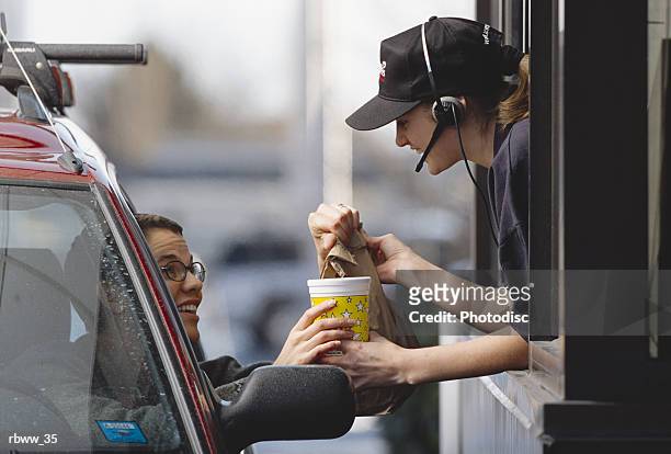 a fast-food employee gives a customer her order - fast food fotografías e imágenes de stock