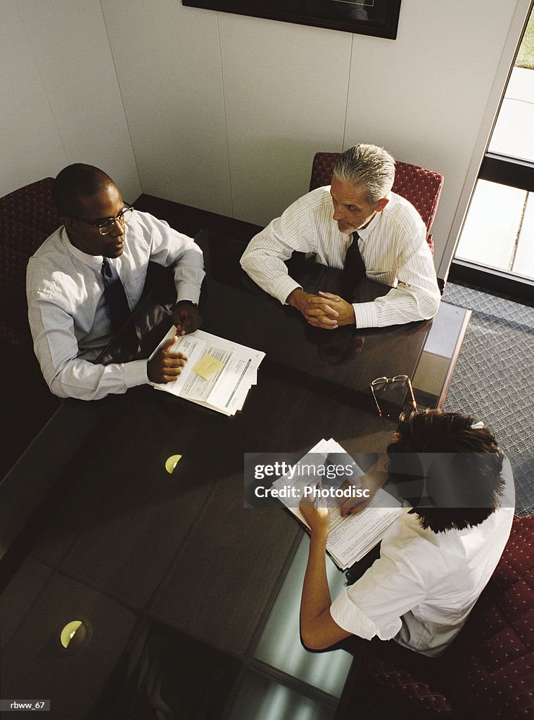 A businesswoman and two businessmen meet in an office to discuss their work
