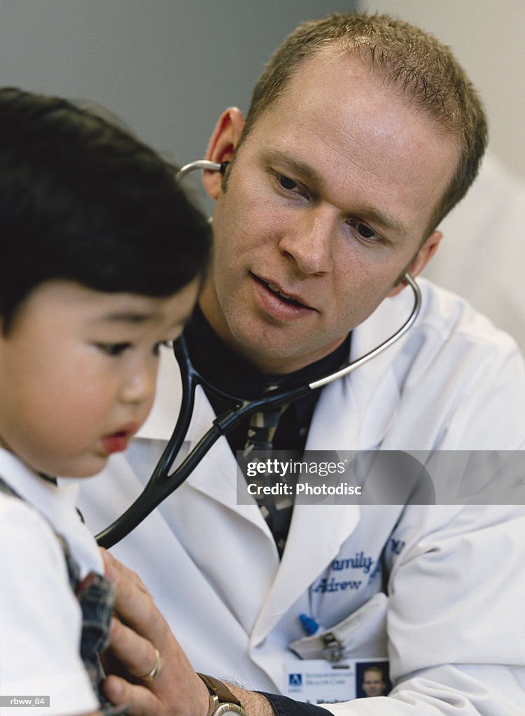 Doctor listening to young boy's (4-6) heart with stethoscope