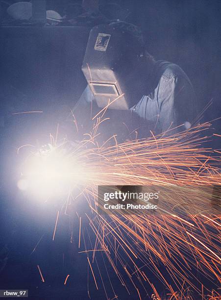 a welder wearing  protective eyewear works on metal while sparks fly - sparks bildbanksfoton och bilder