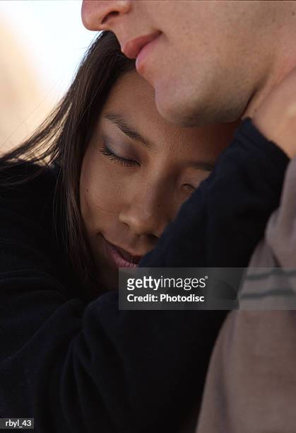 a young woman with her eyes closed is hugging the neck of a young man - is stock pictures, royalty-free photos & images