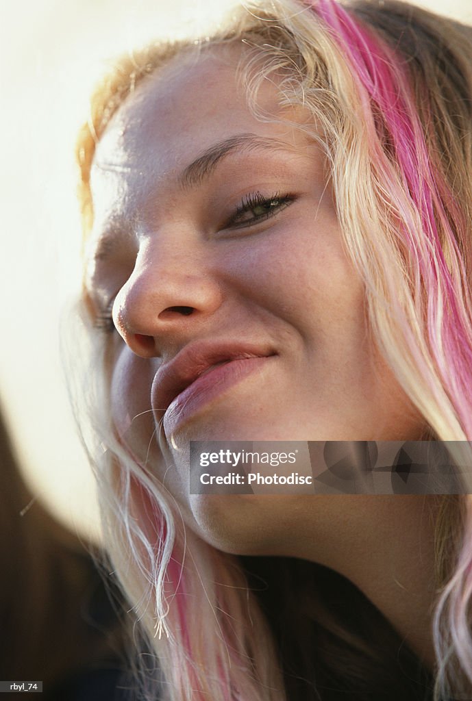 The headshot of a young teenage girl with blond and pink hair who is smiling confidntly at the camera
