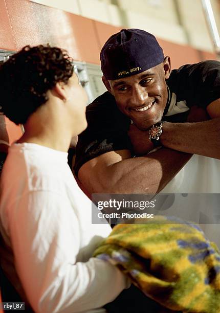 a young man in a blue baseball cap is flirting with a a young woman in a long sleeved white shirt inside a laundromat - long - fotografias e filmes do acervo