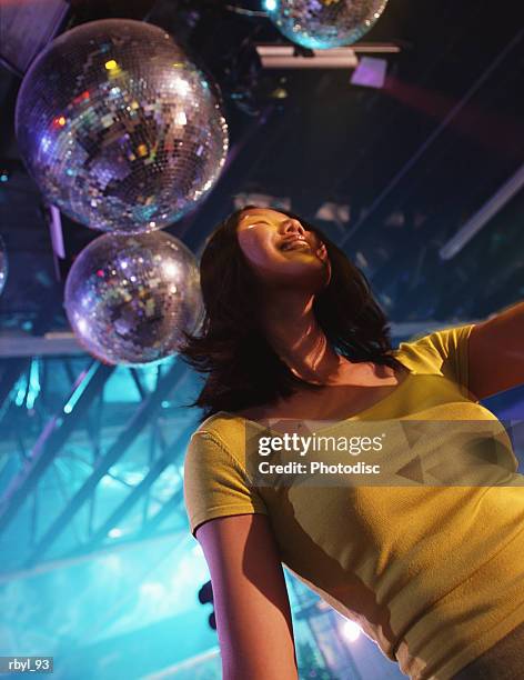 a young woman with long black hair dressed in a yellow shirt is dancing in a nightclub - long - fotografias e filmes do acervo