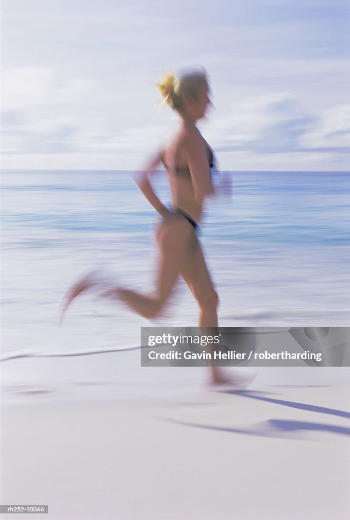 Blurred motion image of a woman jogging on the beach, Mahe Island, Seychelles, Indian Ocean, Africa