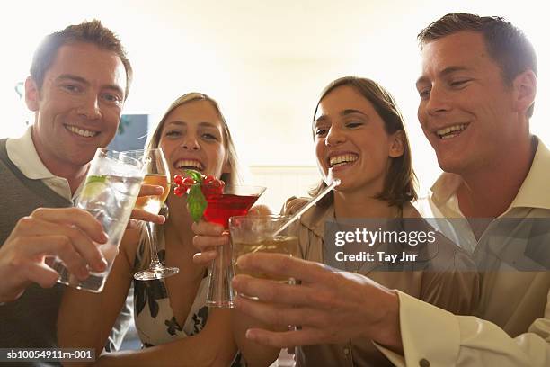 two young couples toasting with drinks, laughing - 4 cocktails stockfoto's en -beelden