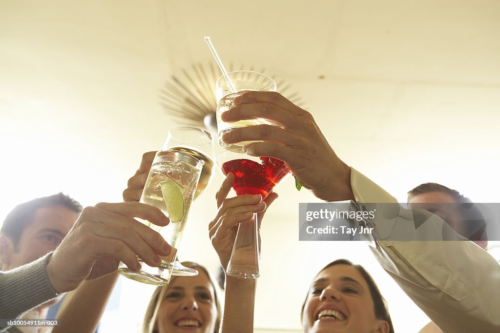 Two young couples toasting with drinks, close-up of hands