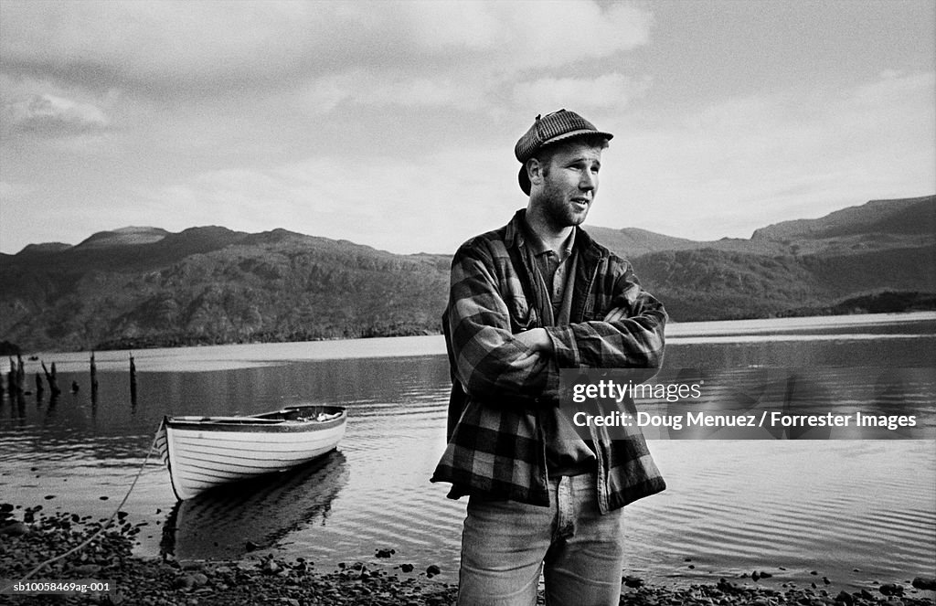 Fisherman with arms crossed at lake shore (B&W)