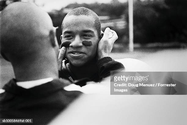 american footballer painting team-mates face, outdoors (b&w) - face paint stock pictures, royalty-free photos & images
