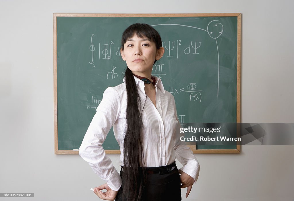 Female teacher standing in front of blackboard, portrait