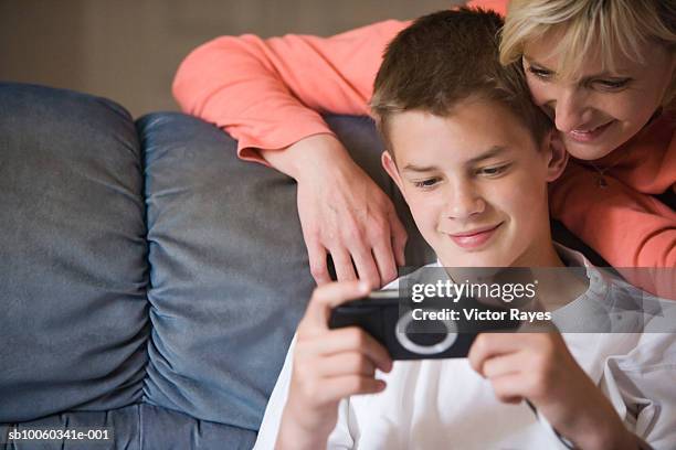 mother and son (10-11 years) on sofa, watching pictures in digital camera - 40 44 years woman stock-fotos und bilder