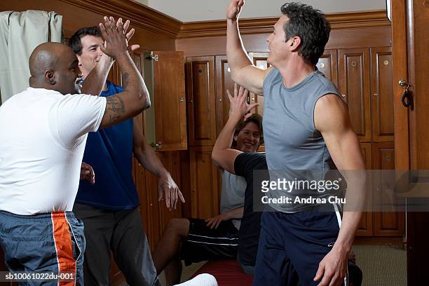 group of men exchanging high-fives in locker room - hi five gym stockfoto's en -beelden