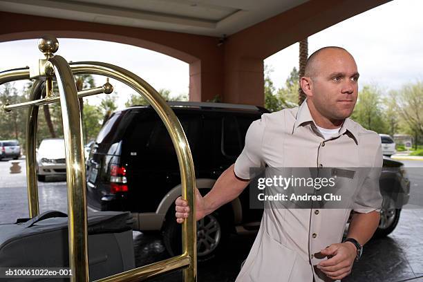 bellhop pulling luggage on luggage cart - bus boy stock pictures, royalty-free photos & images