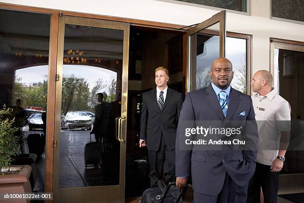 door attendant holding door for business men leaving hotel - door attendant stock pictures, royalty-free photos & images