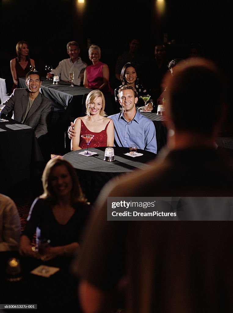 Couple in audience watching comedian, smiling