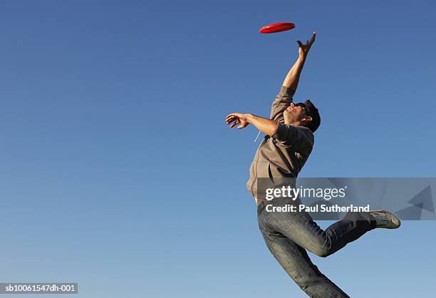 man jumping to catch flying disc - frisbee stock-fotos und bilder