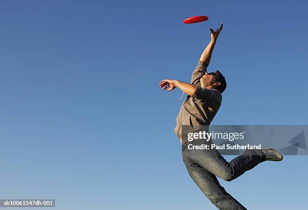man jumping to catch flying disc - frisbee fotografías e imágenes de stock