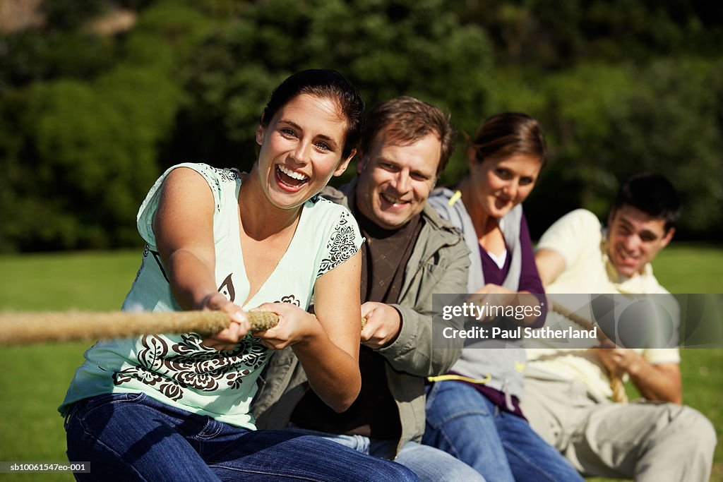 Friends playing tug-of-war in park (differential focus)